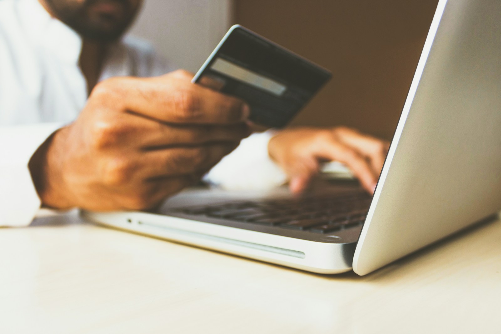 Kredi kartı ve dizüstü bilgisayarla online alışveriş yapan kişi