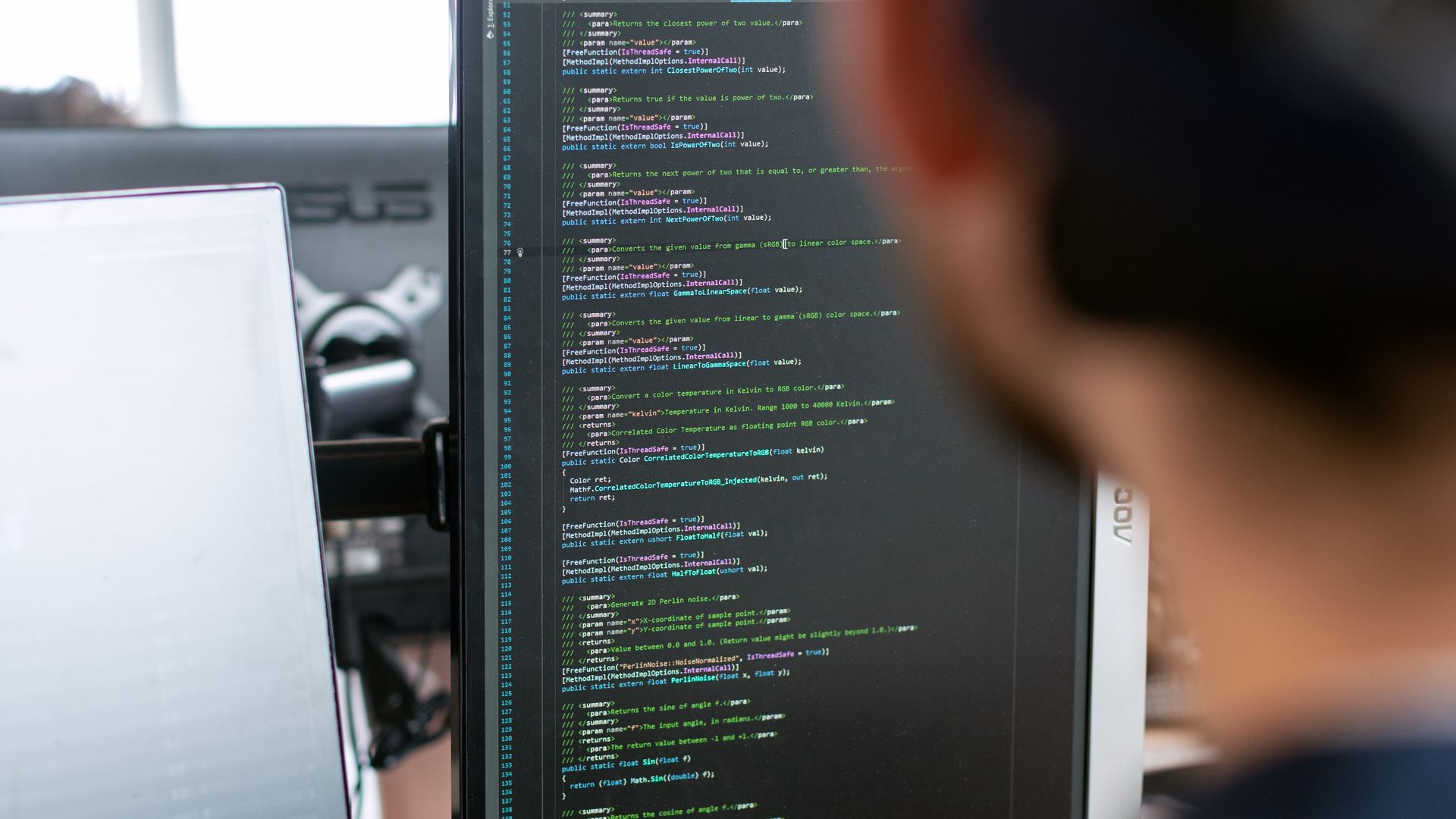 Software developer working at a monitor showing code
